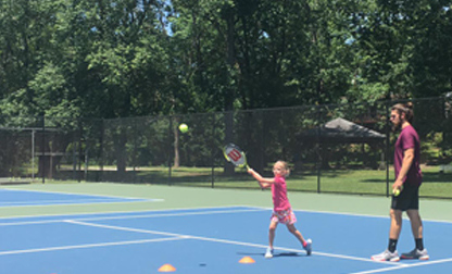 little girl working on her backhand with tennis pro